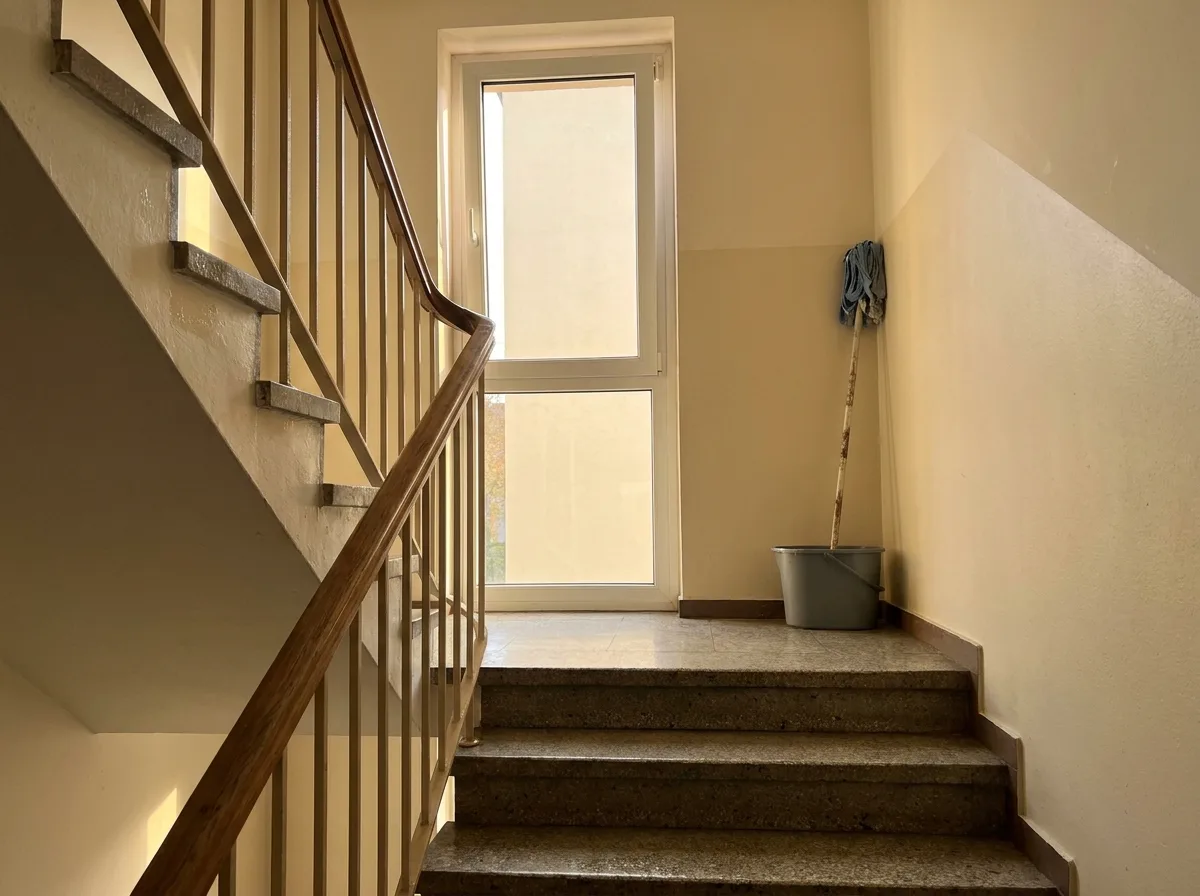 Frisch gewischtes Treppenhaus mit Holzhandlauf im Tageslicht